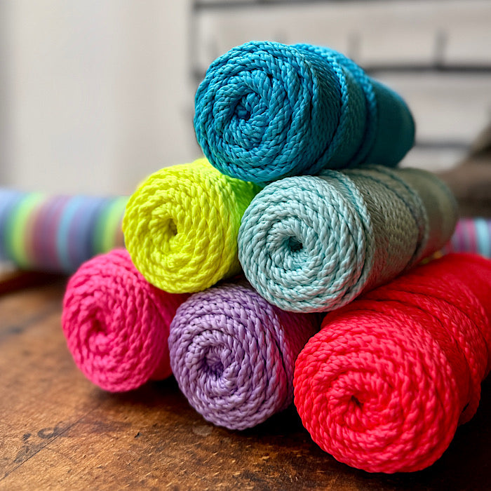 Stack of colorful yarn rolls on a wooden surface
